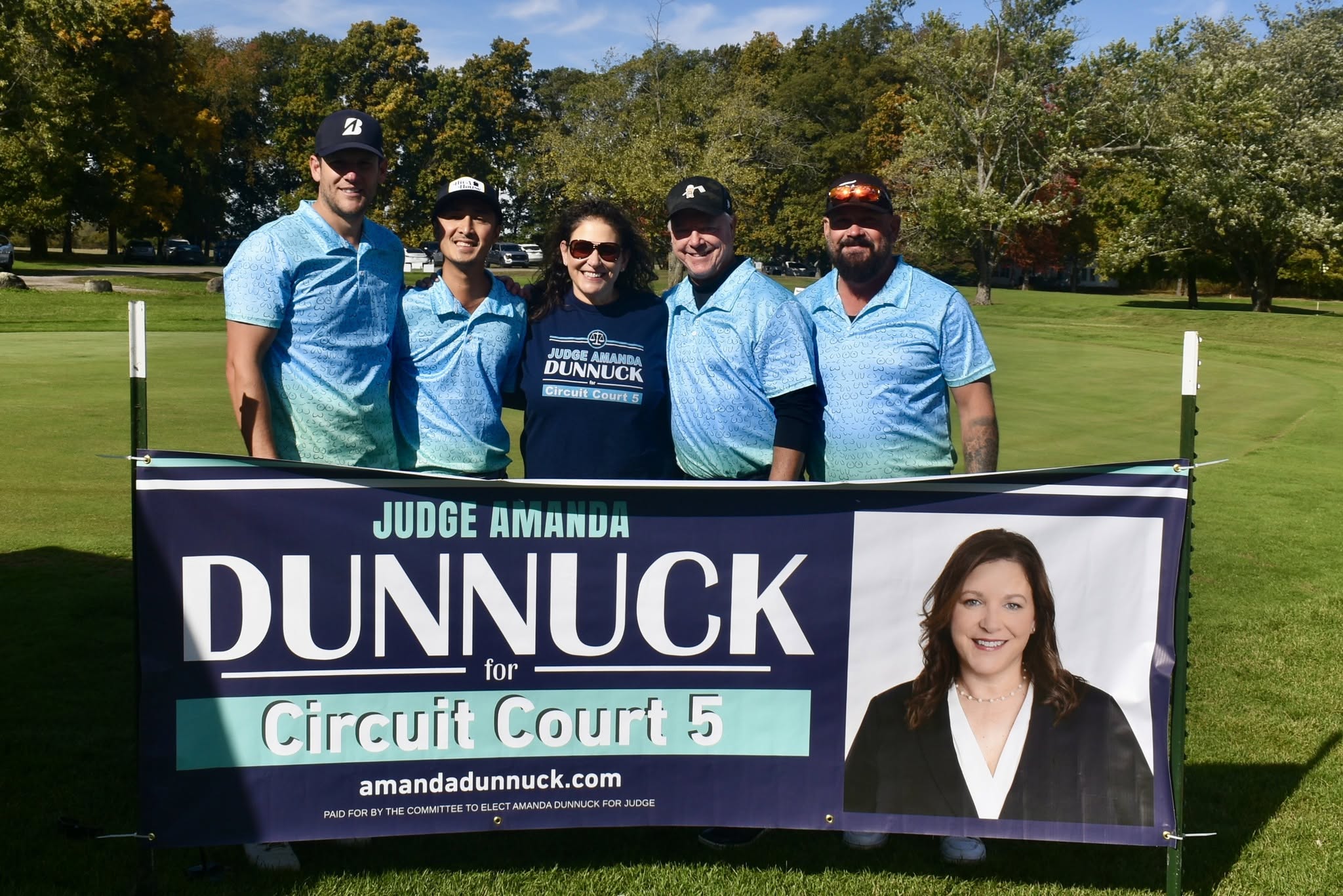 Amanda and 4 golfers standing behind her banner